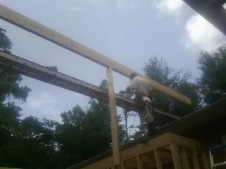 Carpenter setting a ridge beam over a new addition frame — Ice Dam Removal by Roofing Brothers in Climax