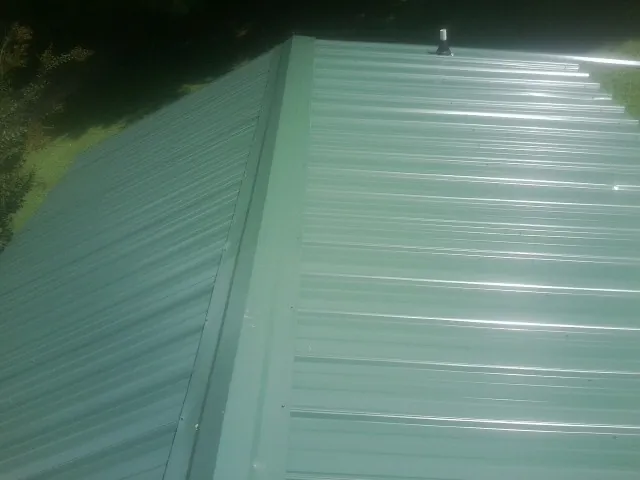New green metal panels meeting at the ridge of a roof — Flat Roof Repair work by our crew in Climax