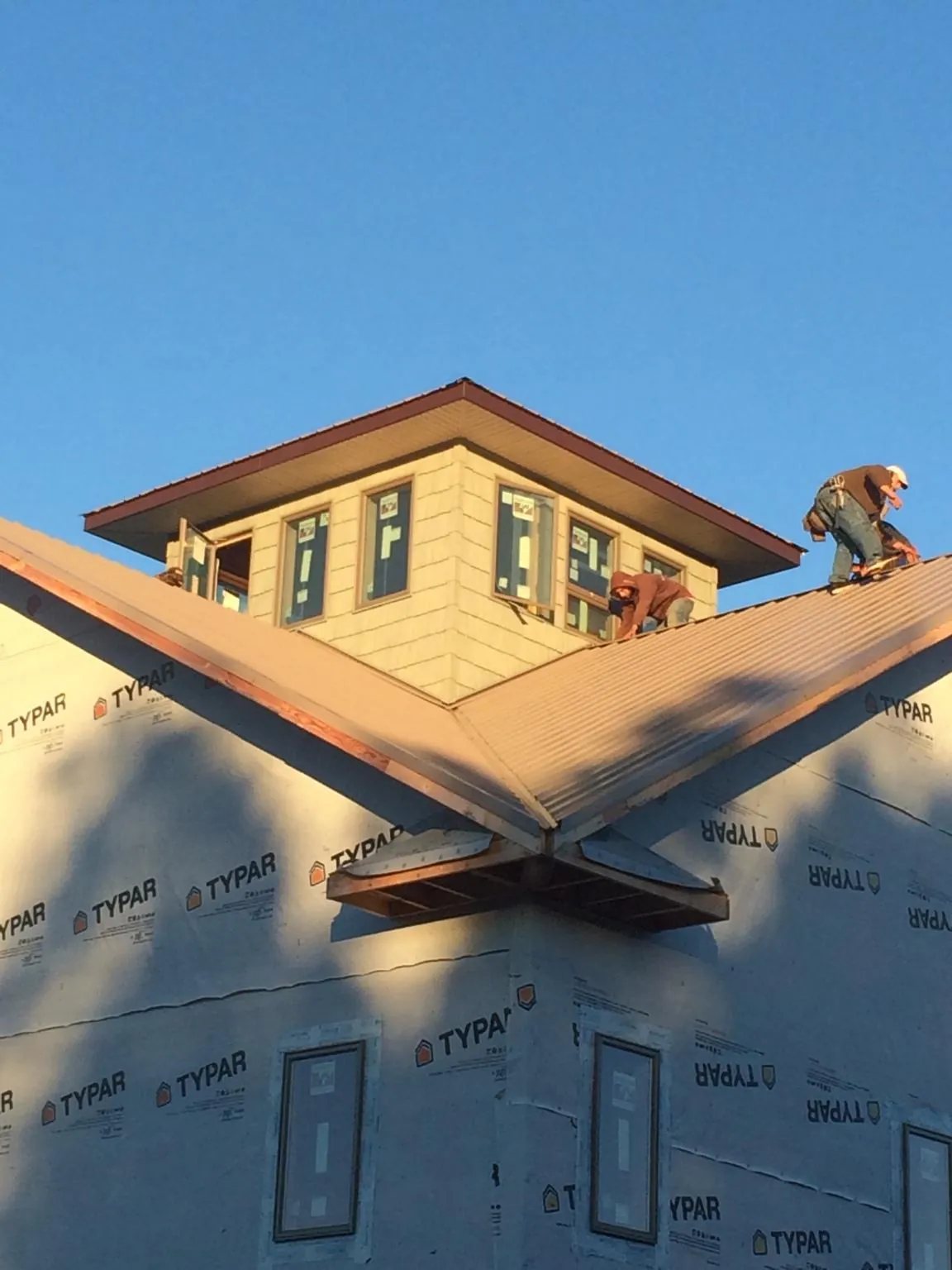 Roofers working around a rooftop cupola on a new metal roof at sunset — Roof Waterproofing in Climax by Roofing Brothers